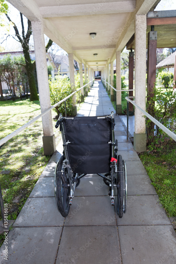 Empty wheelchair in hospital outdoor hallway
