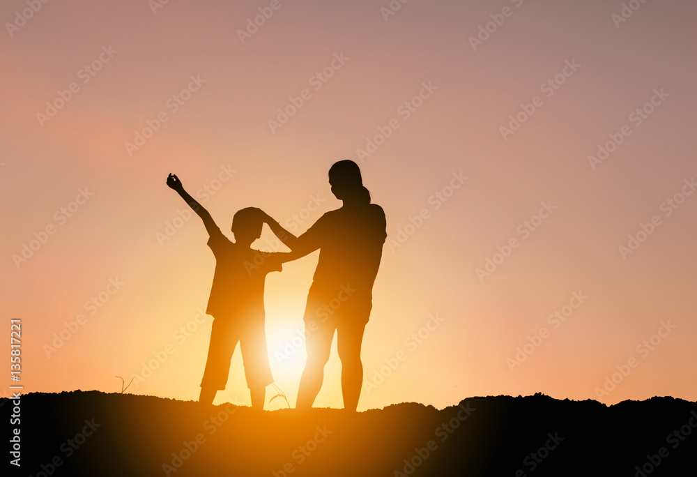 Fototapeta premium Silhouettes of mother and son playing at sunset evening sky background.