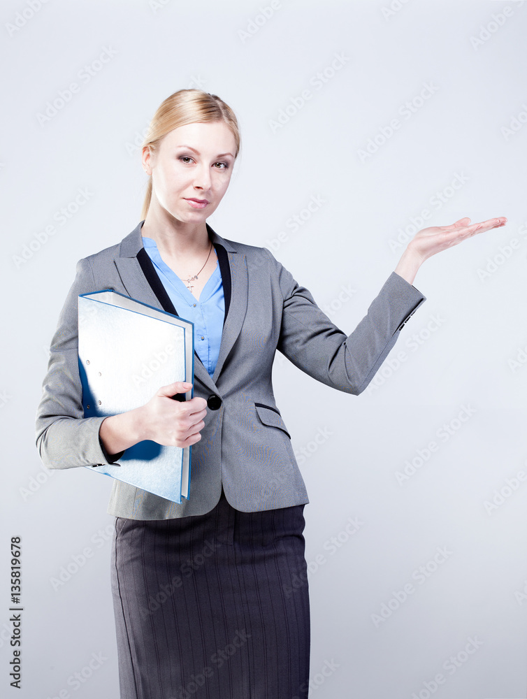 Young business woman pointing open hand palm towards blank space isolated on grey background. Young business woman pointing open hand palm towards blank space isolated on grey background.