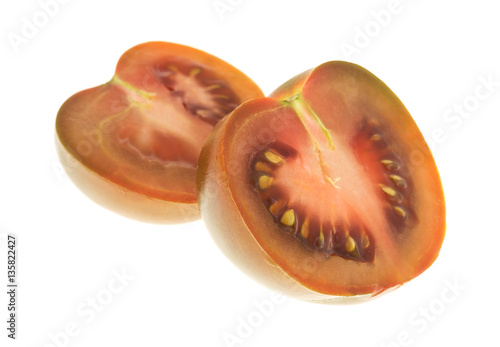 Brown tomato sliced in half side view isolated on a white background.