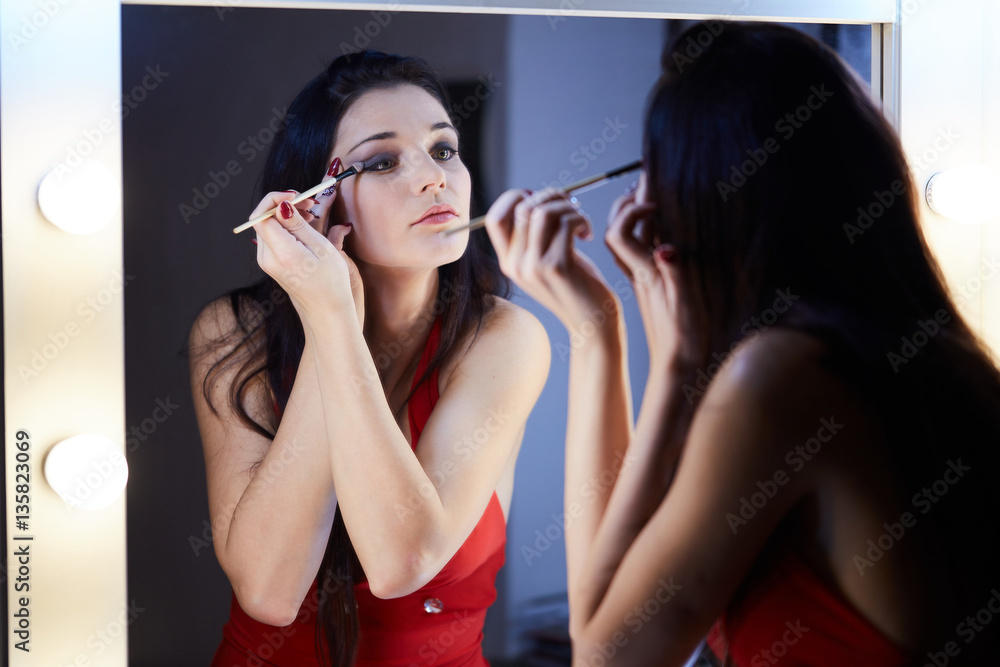Portrait of a beautiful woman as applying makeup near a mirror Portrait of a beautiful woman as applying makeup near a mirror