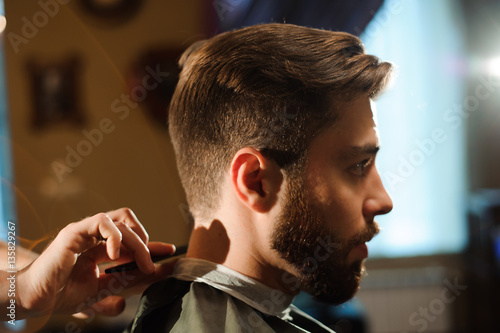 Master cuts hair and beard of men in the barbershop