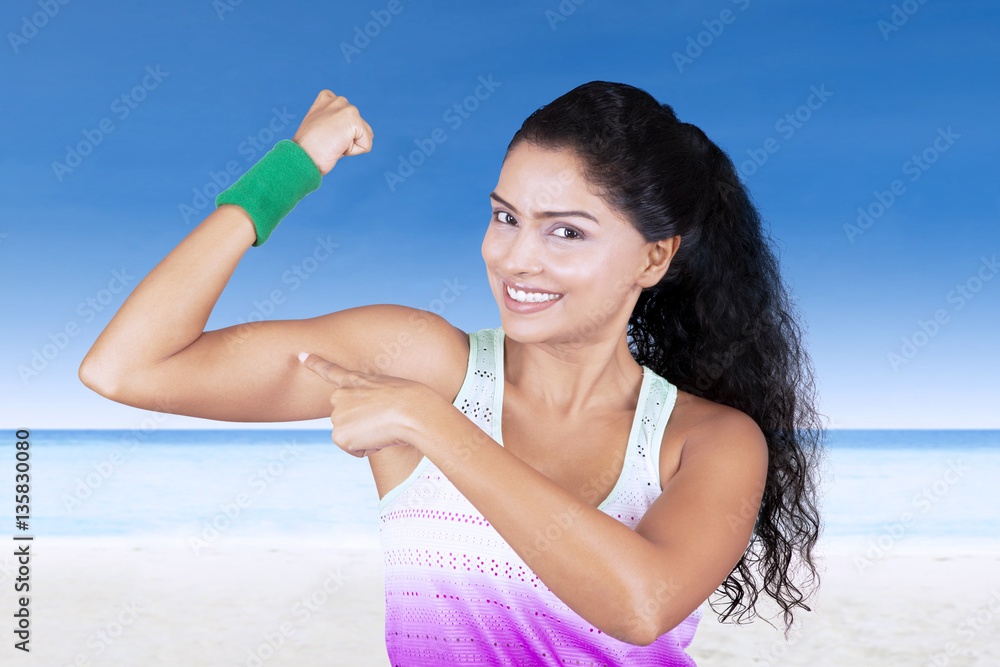 Beautiful woman pointing muscle at beach