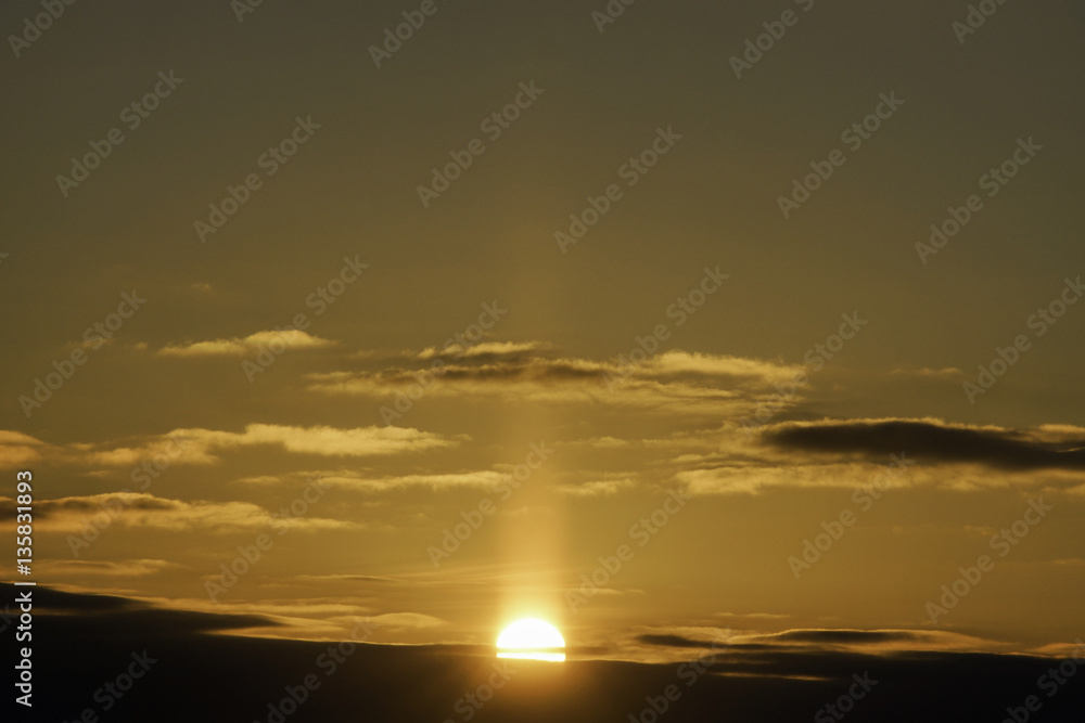 Golden sun halfway above horizon, beautiful orange sunrise