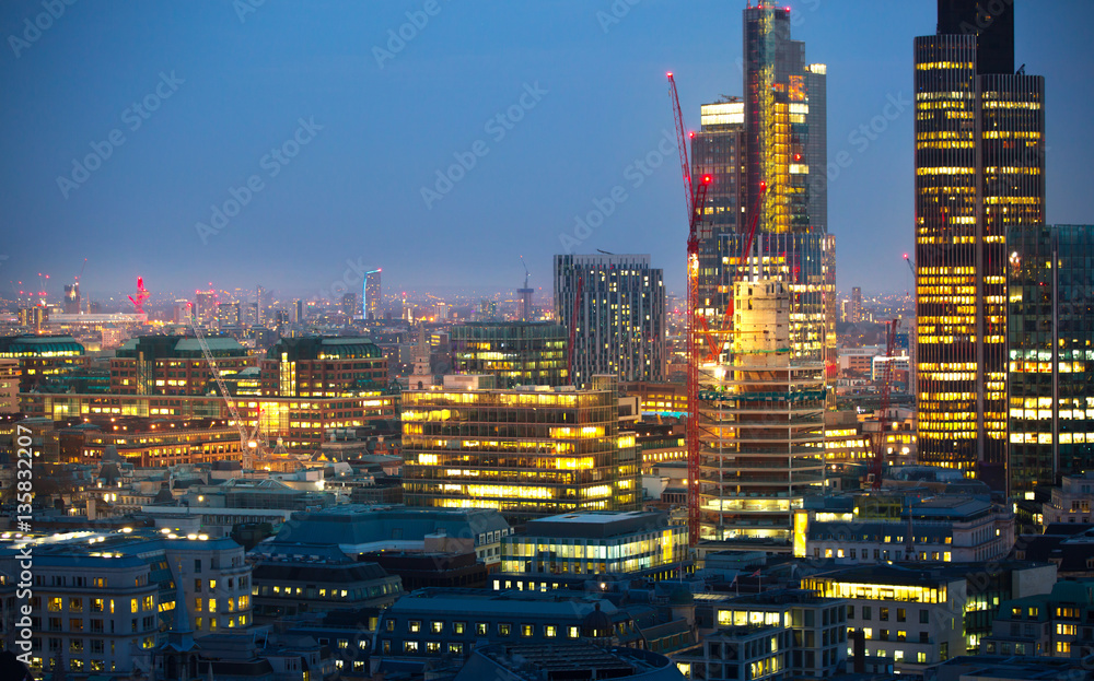 City of London at sunset with lights and reflection. View at the business and banking aria with modern skyscrapers 