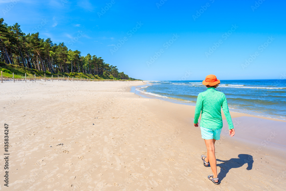 Young woman walking along Lubiatowo beach, Baltic Sea, Poland Young woman walking along Lubiatowo beach, Baltic Sea, Poland