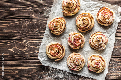 Apple rose puff pastries sprinkled with powdered on baking paper