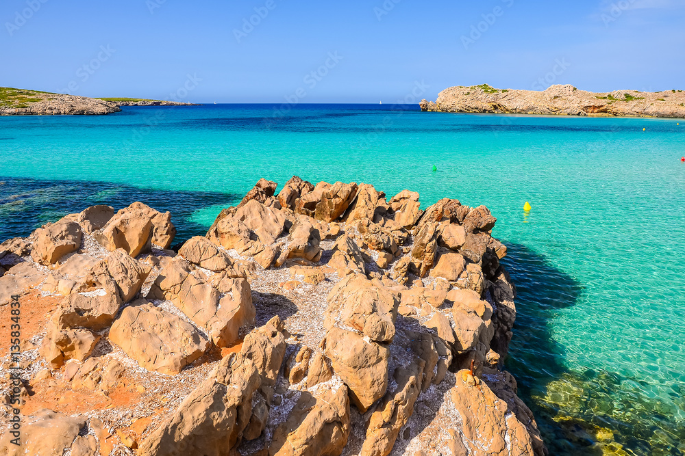 Rocks in Cala Turqueta bay with azure sea water, Menorca island, Spain Rocks in Cala Turqueta bay with azure sea water, Menorca island, Spain