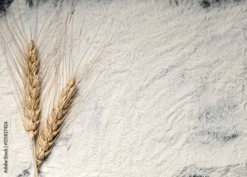 background from the spilled flour and wheat ears on a black baking tray