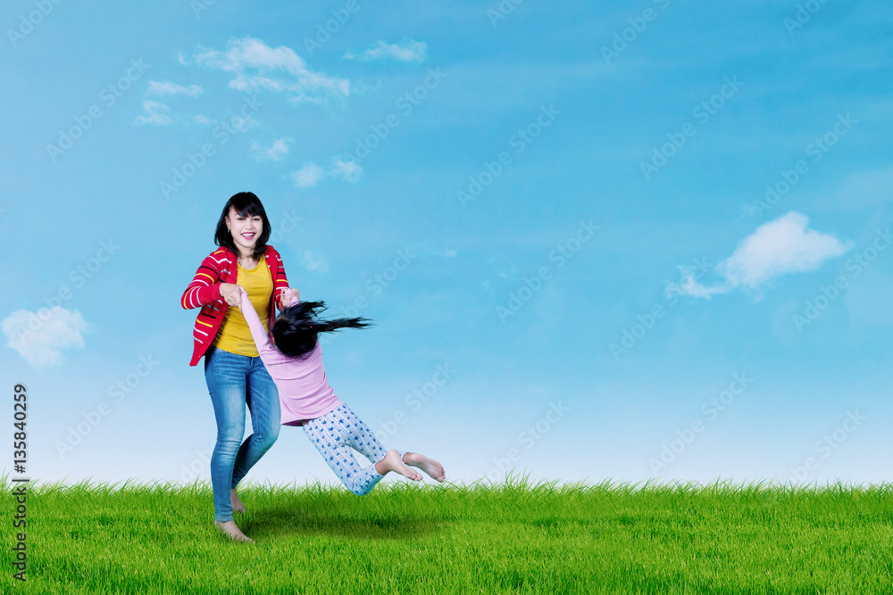 Mother swinging her daughter on meadow Mother swinging her daughter on meadow
