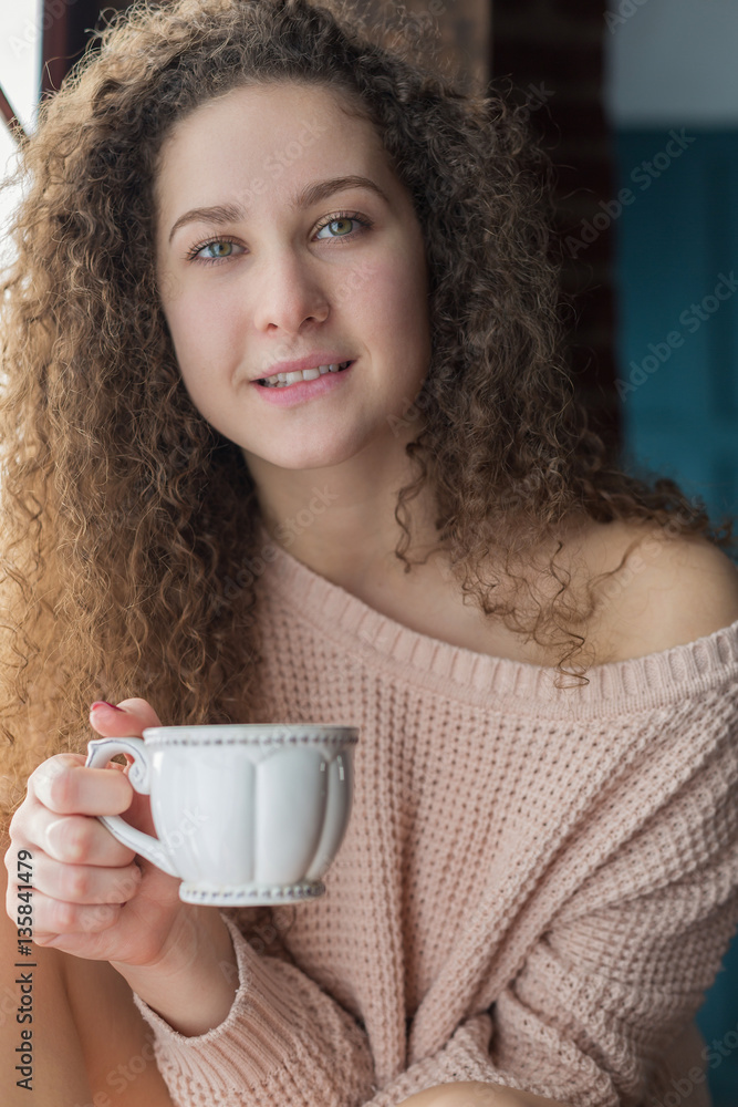 Pretty girl on a windowsill with cup in her hands Pretty girl on a windowsill with cup in her hands