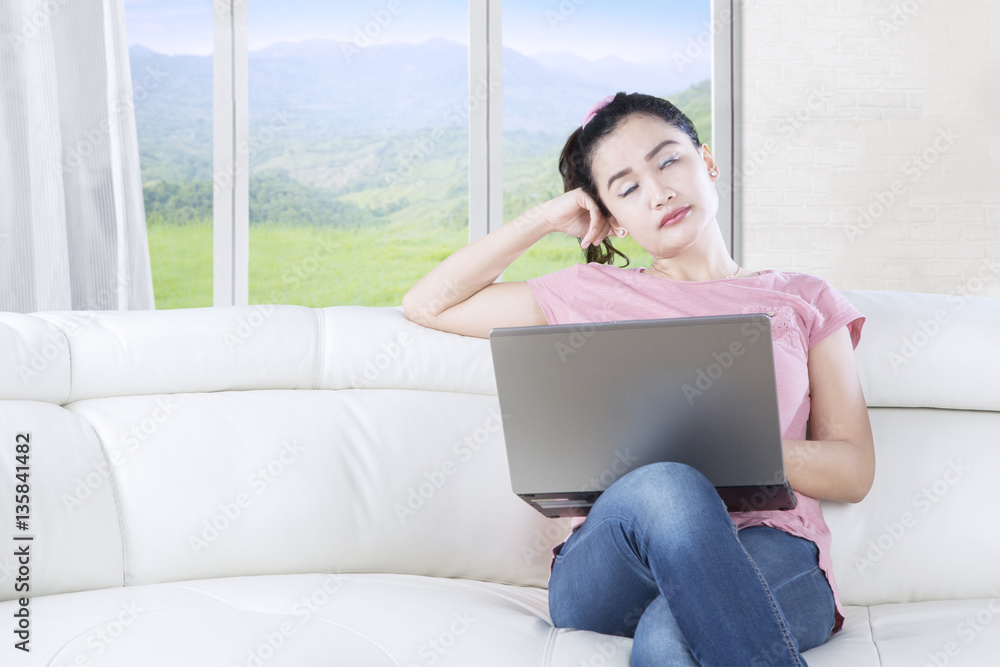 Sleepy woman with laptop in living room Sleepy woman with laptop in living room