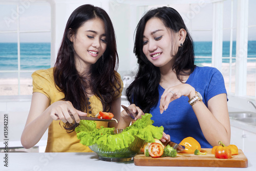 Two girls preparing vegetables salad