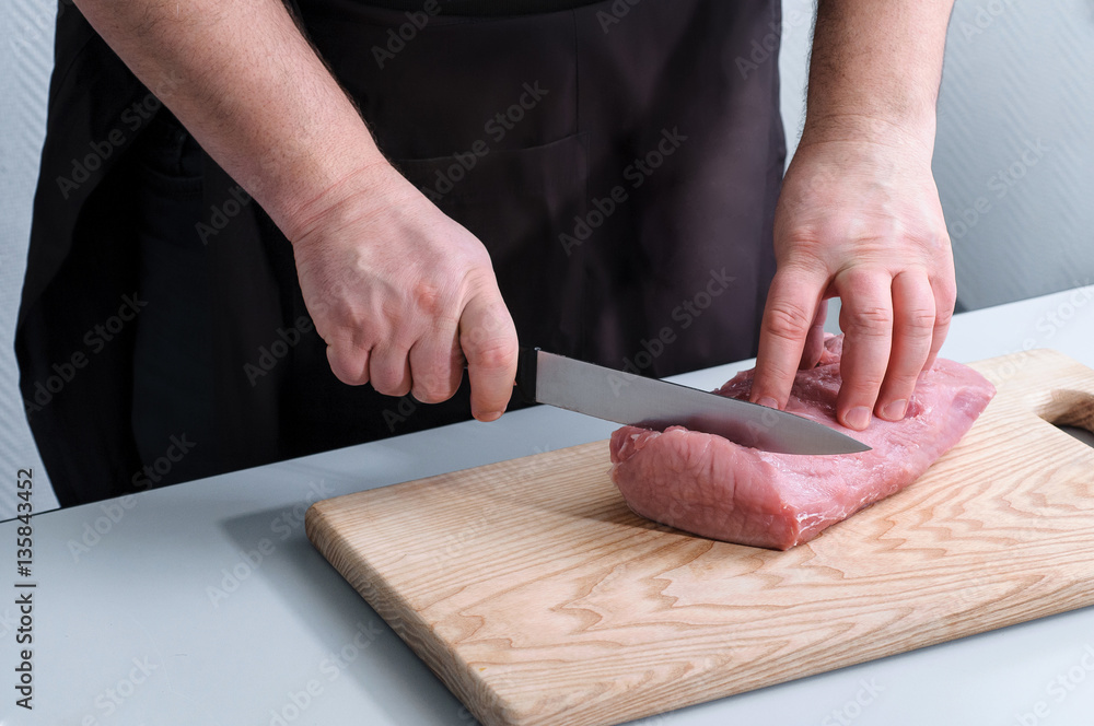process of cutting raw beef meat on a cutting board
