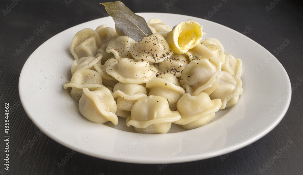 Russian dumplings in a white plate on a black background Russian dumplings in a white plate on a black background