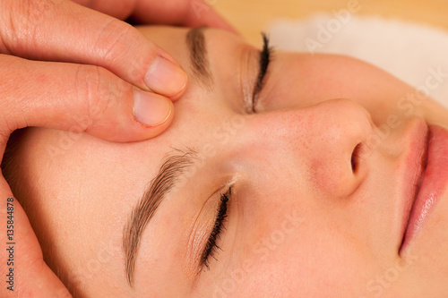 Beautiful blonde woman having a face massage in spa salon
