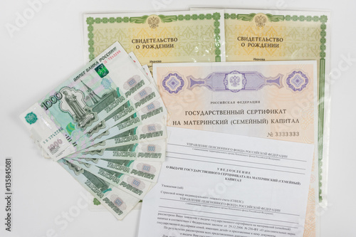 On a white background are two of a birth certificate, a certificate for maternity capital, receipt of a notice of a certificate and a packet of money © madhourse