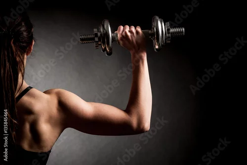 Obraz Kobieta o atrakcyjnym kroju pasuje do hantli jako koncepcja fitness