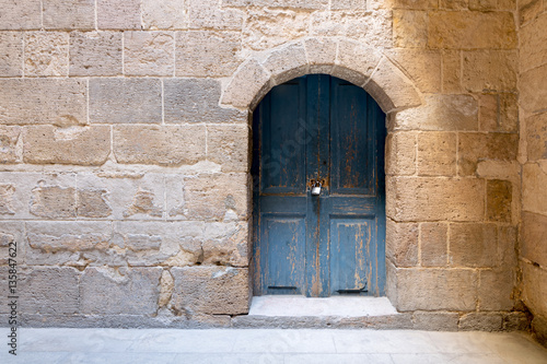 Blue wooden stained aged vaulted ornate door and stone wall © Khaled El-Adawi