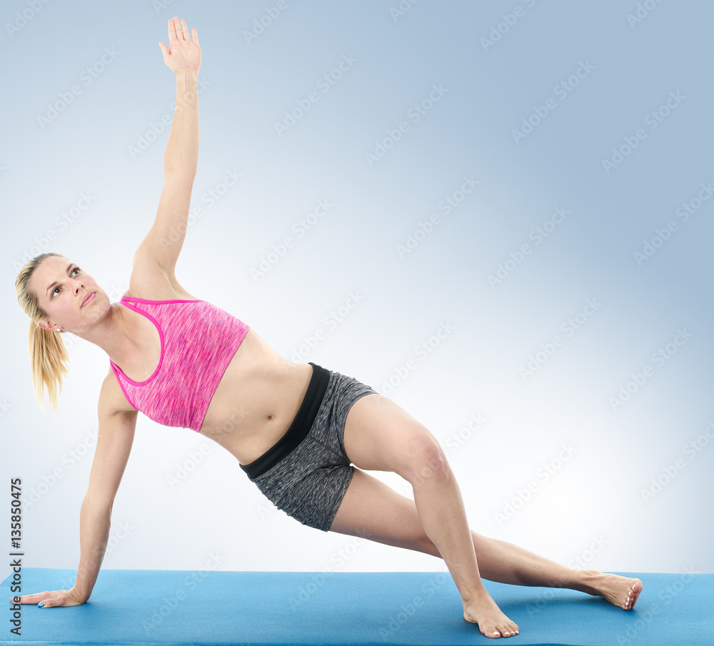 Young woman doing full body yoga exercise  on blue mat
