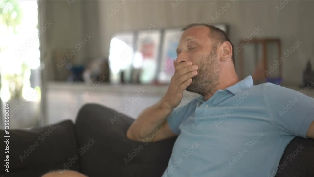 Young man yawning and going to sleep on sofa at home, 4K
Young man yawning and going to sleep on sofa at home, 4K