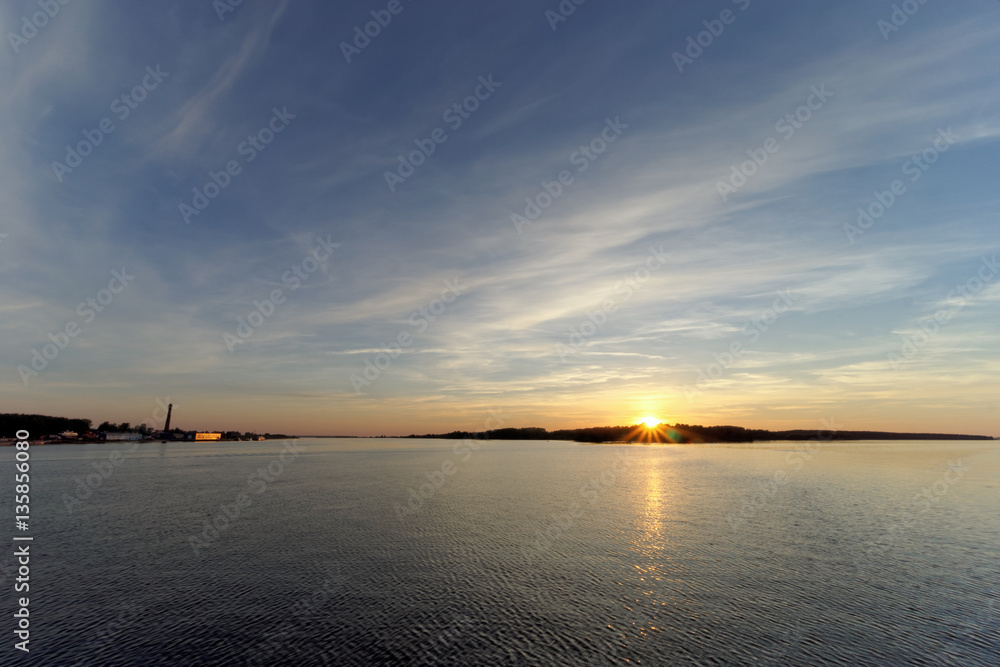Obraz premium A view of the calm golden sunset on the river with the sun reflected in it, Volga, Russia