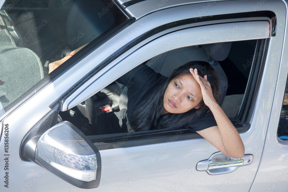 Woman sticking out of the open car window and with shading hand looks into the distance. Woman sticking out of the open car window and with shading hand looks into the distance.