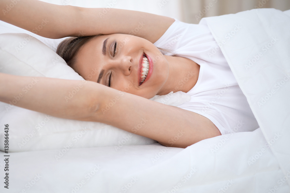 Woman stretching in bed after wake up, entering a day happy and relaxed after good night sleep. Sweet dreams, good morning, new day, weekend, holidays concept Woman stretching in bed after wake up, entering a day happy and relaxed after good night sleep. Sweet dreams, good morning, new day, weekend, holidays concept