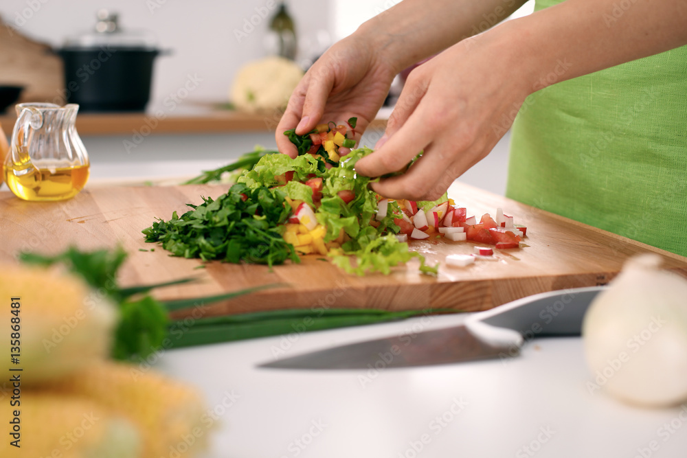 Close up of  woman's hands cooking in the kitchen. Housewife slicing ​​fresh salad. Vegetarian and healthily cooking concept