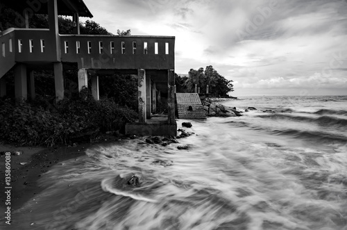 black and white image wave hitting the coastline with dramatic cloud background