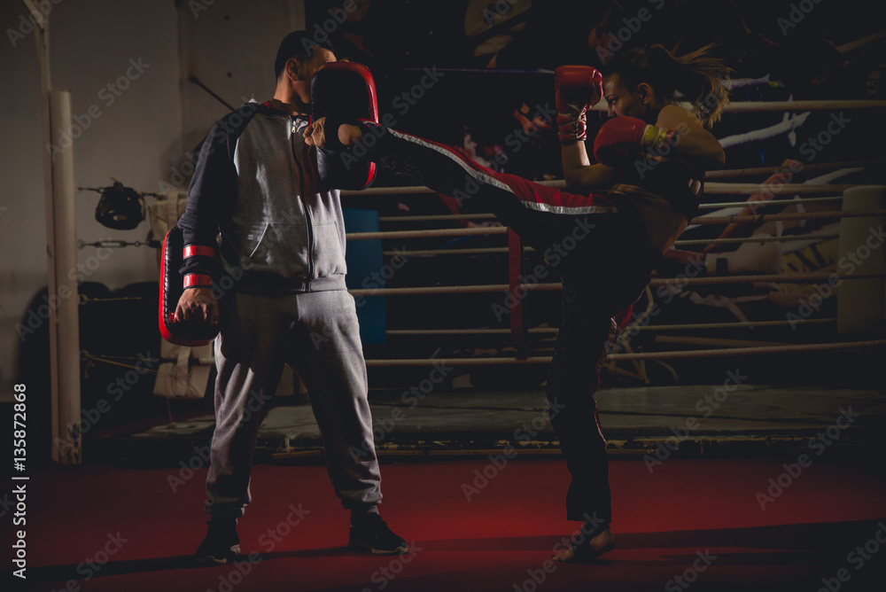 Naklejka premium Girl kickboxer sparring with coach