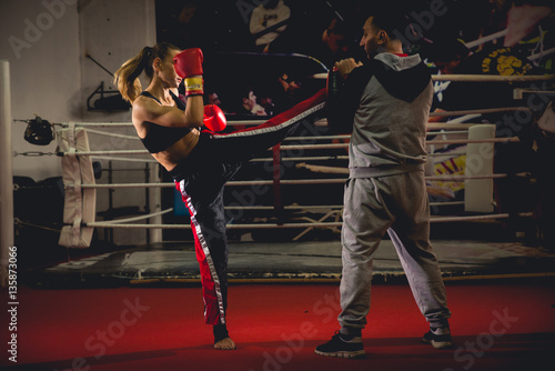 Girl kickboxer sparring with coach
