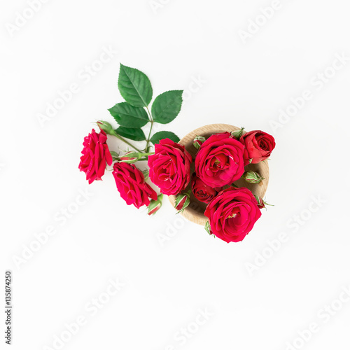 Red roses and green leaves on white background. Flat lay  top view. Valentine s background