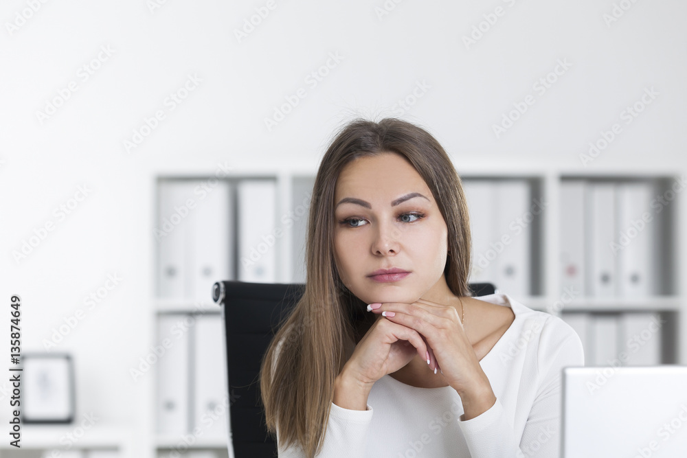 Portrait of pensive blond woman in white in office