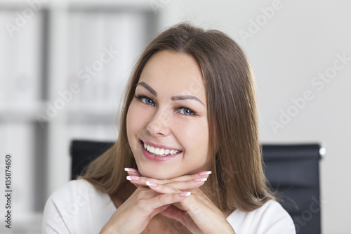 Close up of smiling woman with hands under chin