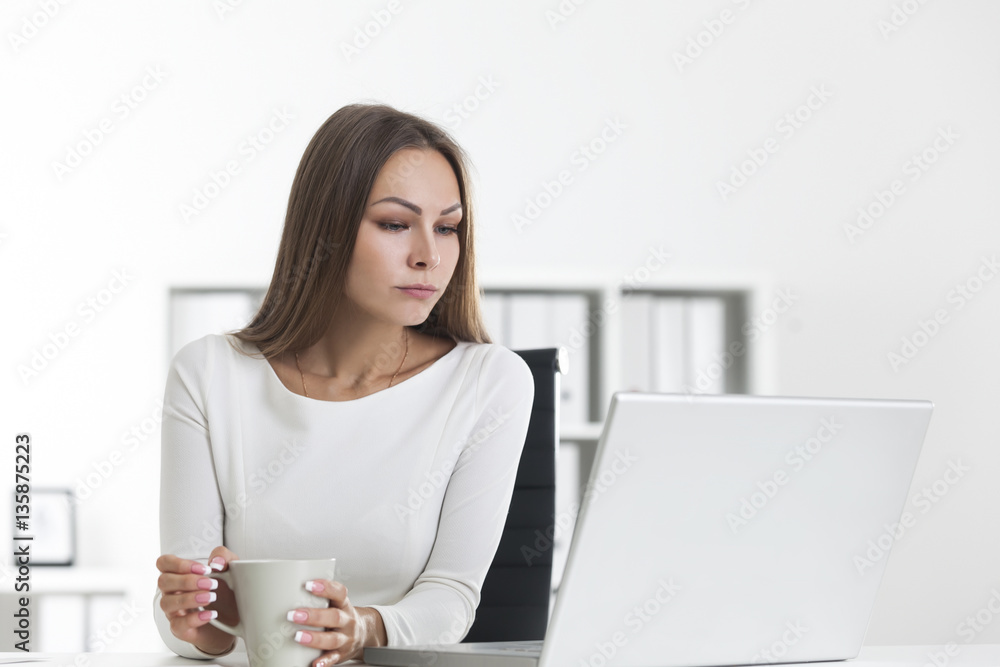 Pensive woman with coffee in white office Pensive woman with coffee in white office
