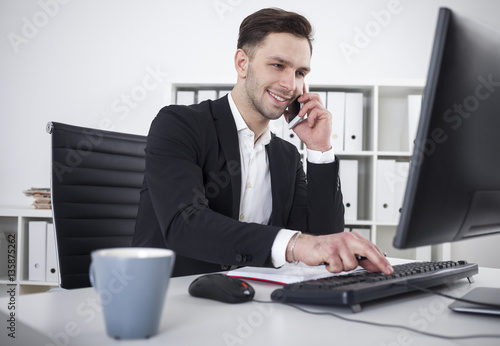 Smiling businessman with a smartphone typing