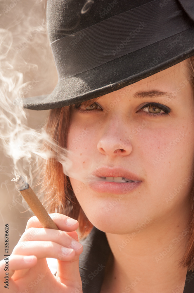 Foto de Pretty young woman smokes a cigar outside. Caucasian