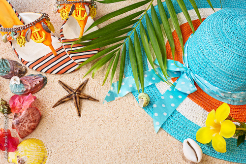 Sandals, hat and sea shelles on the sand. Summer beach concept