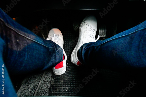 close up man foot step on the car accelerator, wearing white shoe and blue jean  © Chayakorn