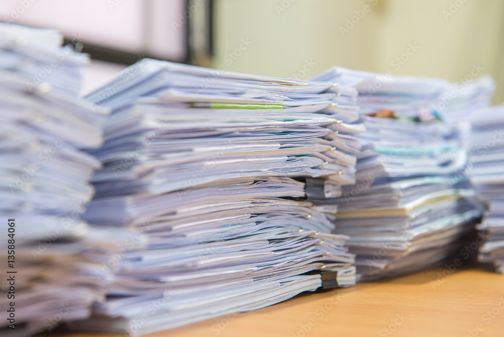 documents on desk stack up high waiting to be managed documents on desk stack up high waiting to be managed