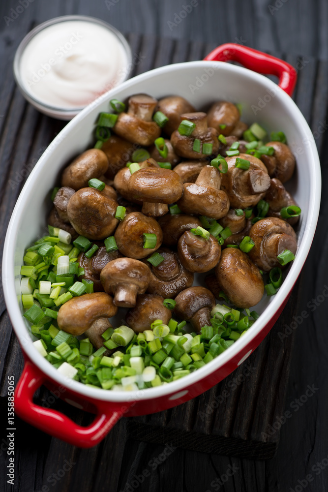 Bowl with whole fried champignons, green onion and sour cream Bowl with whole fried champignons, green onion and sour cream