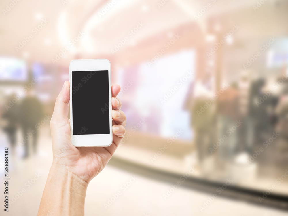 Hands holding mobile phone with blurred image of shopping mall