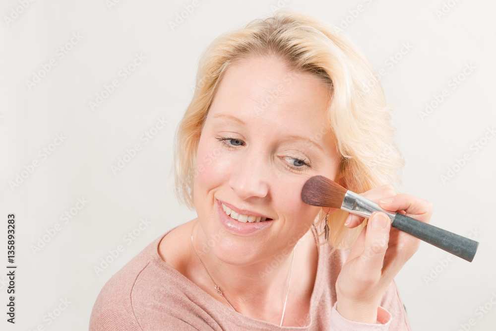 Fototapeta premium Blonde Lady Smiling and Applying Make-Up