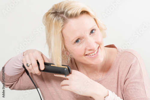 Smiling Lady Styling Her Hair with Straghtening Iron