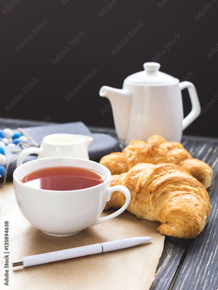 French croissant, glasses, tea and notebook. Workplace concept French croissant, glasses, tea and notebook. Workplace concept