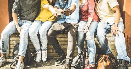 Group of multiculture friends using smartphone on urban background - Technology addiction concept in youth lifestyle disinterested to each other - Always connected people on modern mobile smart phones photo