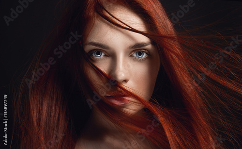 Sexy beautiful redhead girl with long hair. Perfect woman portrait on black background. Gorgeous hair and deep eyes. Natural beauty, clean skin, facial care and hair. Strong and thick hair. Flower photo