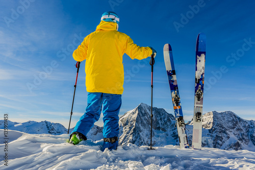 Fototapeta Mountaineer backcountry ski resting along a snowy ridge with ski