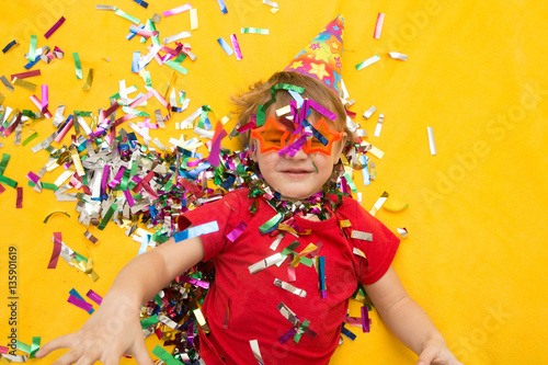 Happy kid celebrating party with blowing confetti top view 